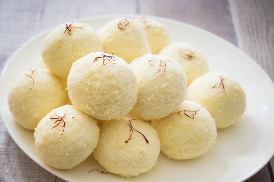 A close-up of light-colored, soft Kacha Golla sweets on a white plate, showcasing their unique texture.